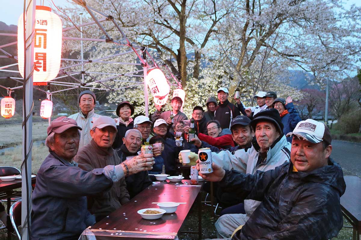 地元が誇る桜のもとで花見会を楽しむ栗林町砂子畑地区の住民ら＝19日夕方