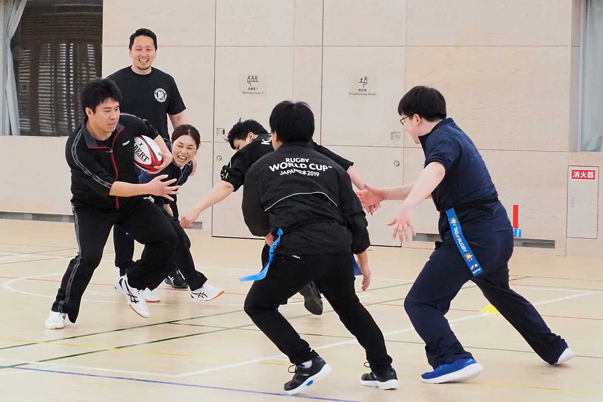 タグラグビーのミニゲームに挑む新人職員。先輩職員の佐伯悠さん（左奥）が見守る