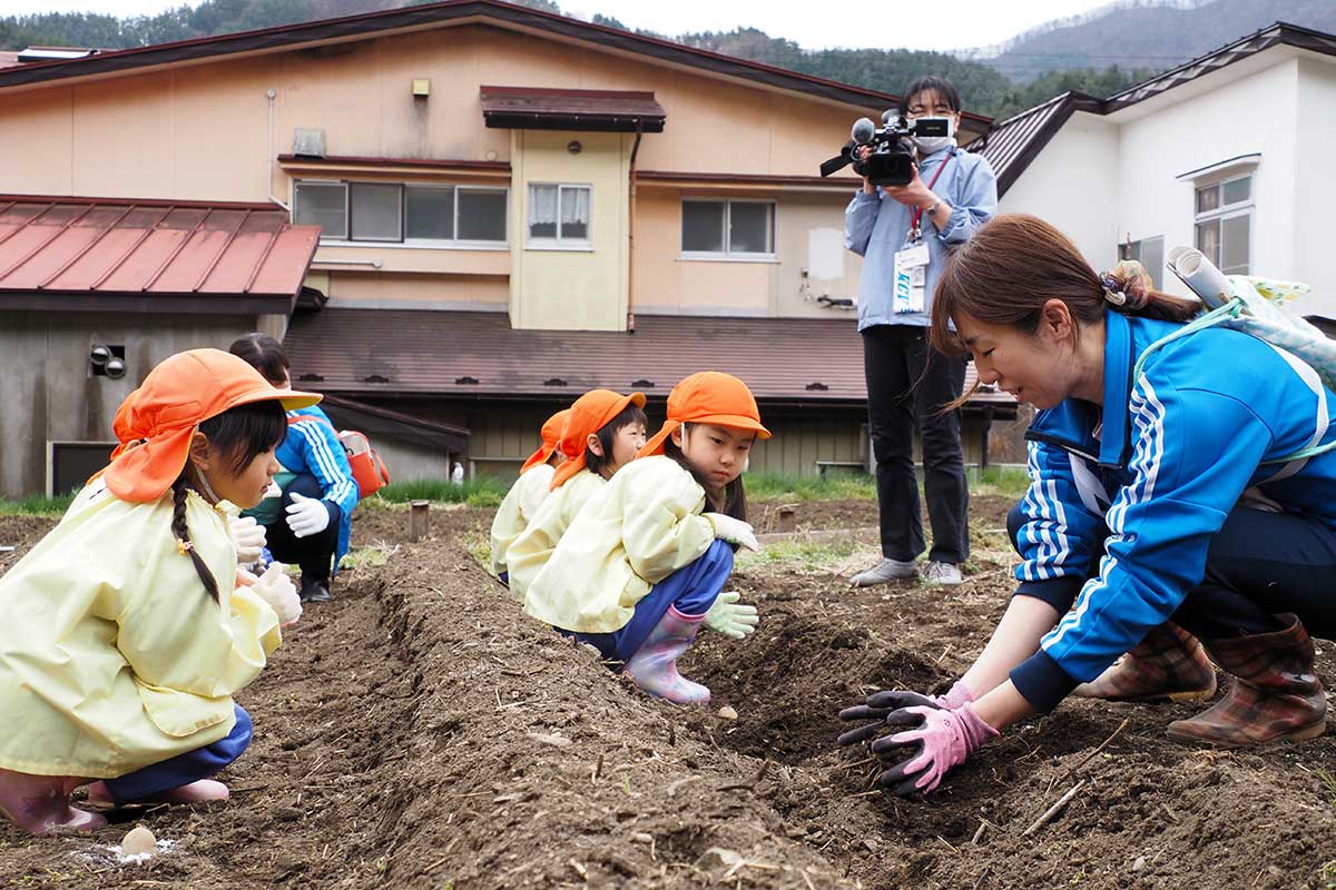 保育教諭（右）の実演をじっと見つめる子どもたち