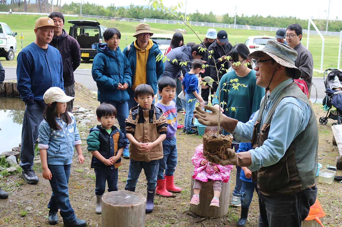植樹するエゾエノキについて説明する菊地利明さん（右）。エゾエノキには国蝶「オオムラサキ」が卵を産み付ける
