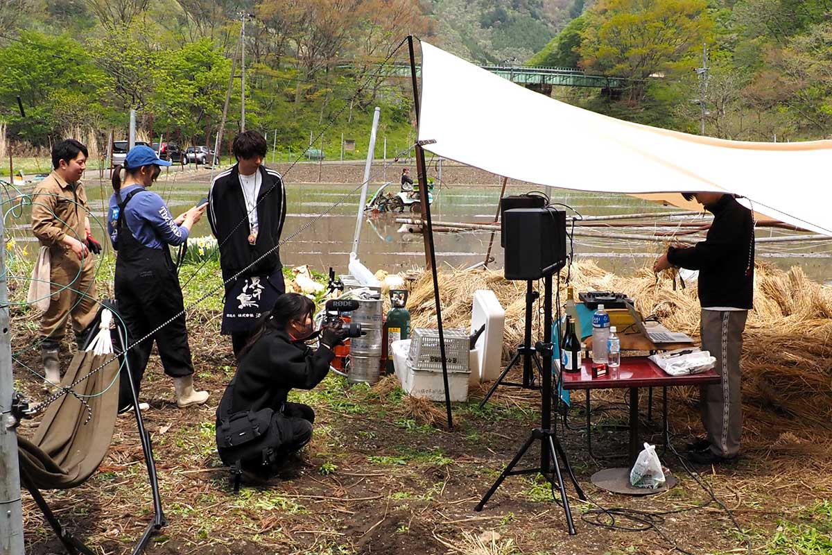 特設の音楽ブースの奥で田植え機が行き交う
