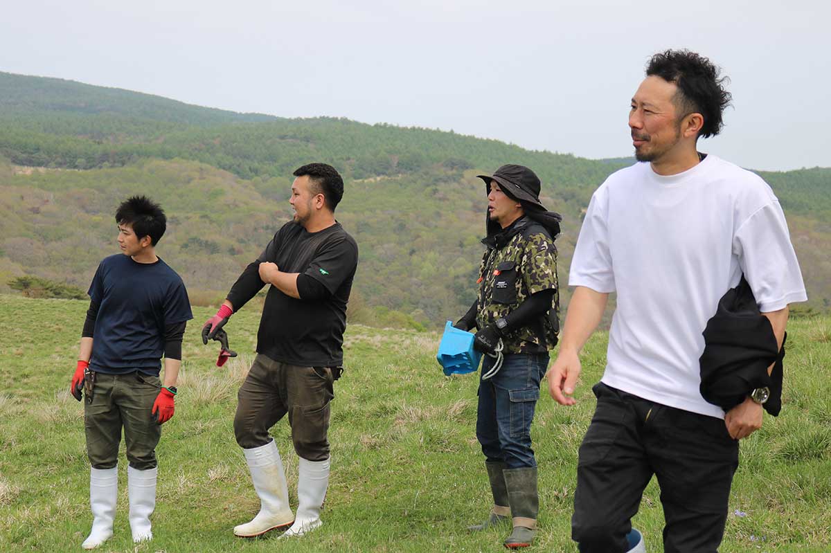 放牧した牛の様子を眺めるエム牧場の吉田和社長（右）と同社従業員ら