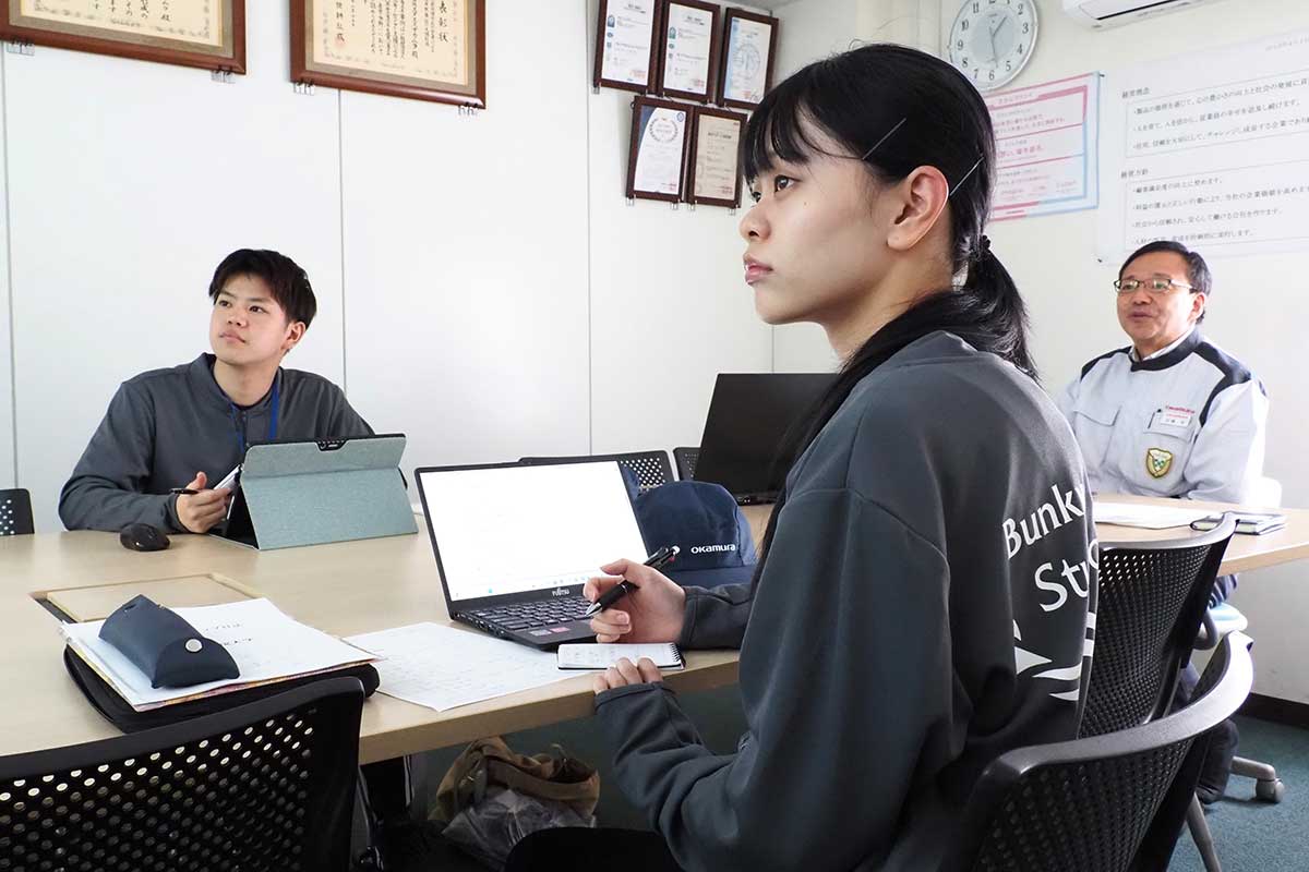 佐藤裕副社長（右奥）の説明に耳を傾ける関波音さん（手前）、松本将汰さん＝5月21日
