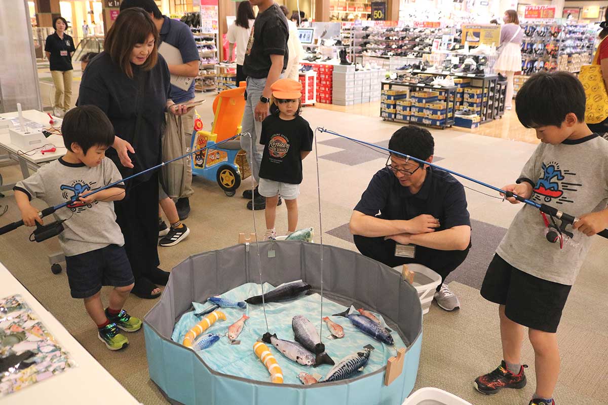魚の頭の先に付いた金属に釣り糸の先端の電磁石を合わせてから手回し発電機を回す