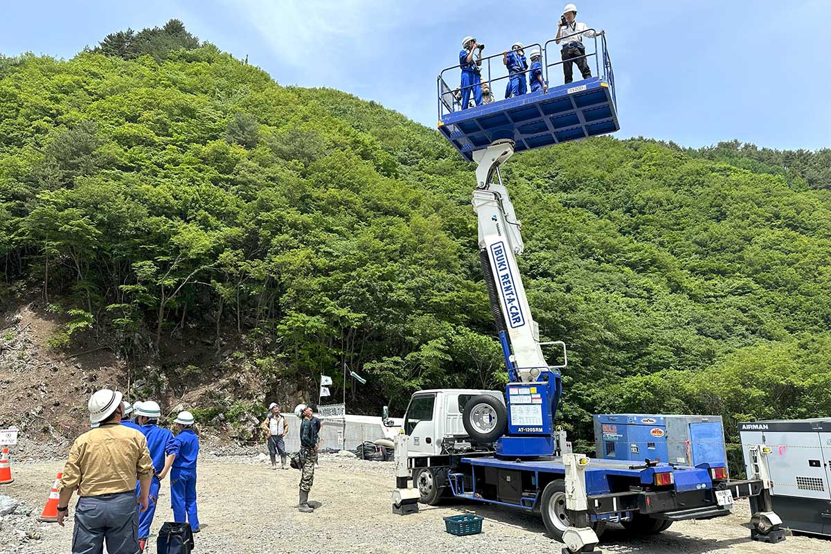 高所作業車に乗って工事現場を見渡す生徒ら
