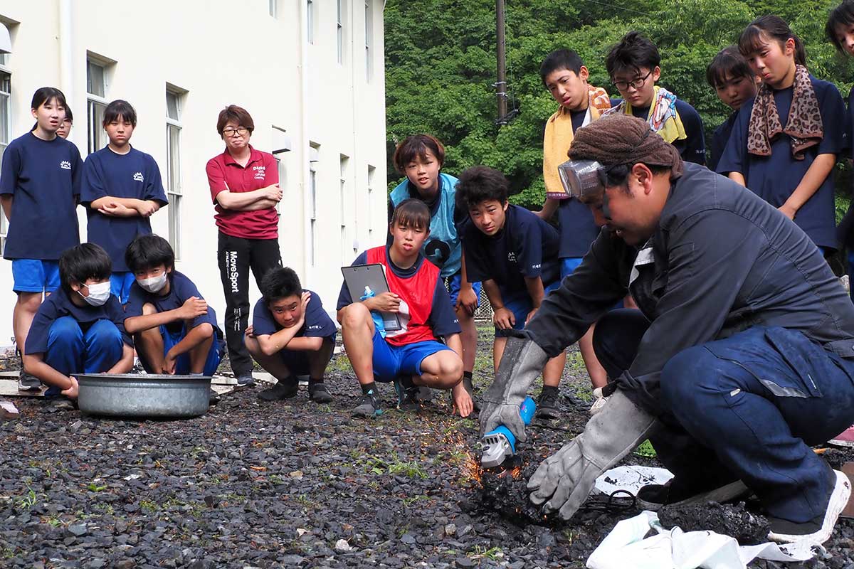 塊を磨くと火の粉が舞い、鉄づくりの成功を実感する生徒ら