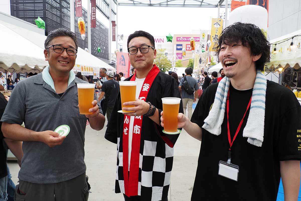 実行委の仲間と笑顔を重ねる小澤伸之助さん(中)