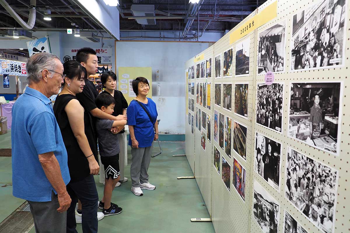 買い物に訪れた客や帰省した人らが展示に足を止めている