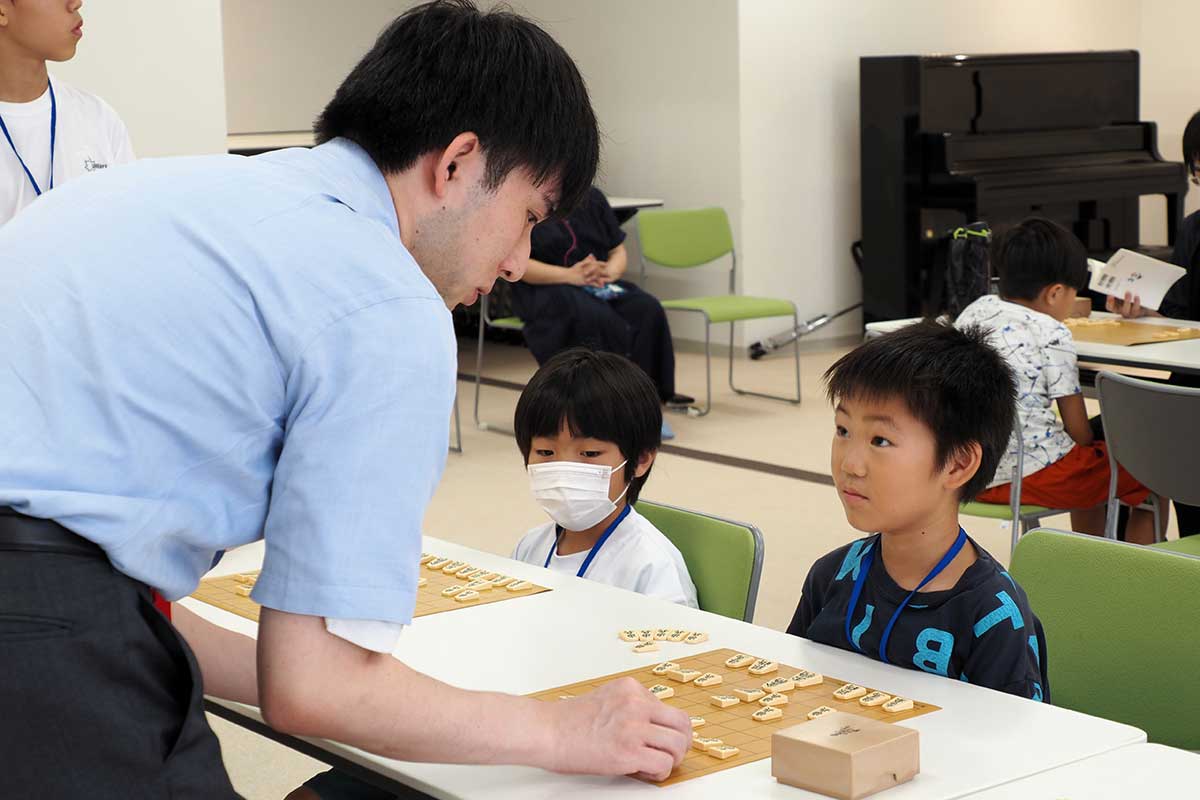 感想戦で戦法を教わる子ども。しっかりと耳を傾ける