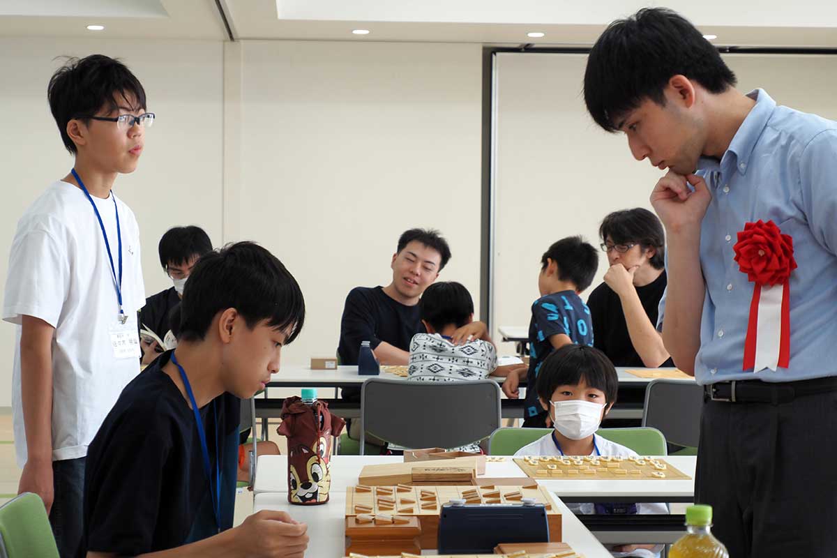 盤を挟んで駒で対話する小山四段（右）と高校生