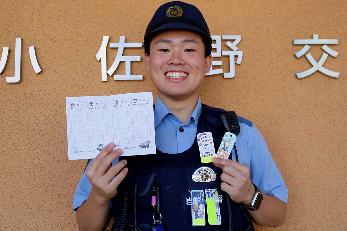 「今年も作りました!」 手作りの反射材キーホルダーと地域安全血圧手帳をPRする小佐野交番の矢神海輝巡査