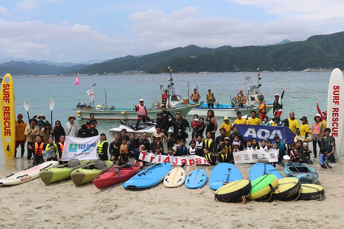 協力団体、企業のフラッグを掲げ、記念写真に収まる参加者とスタッフら