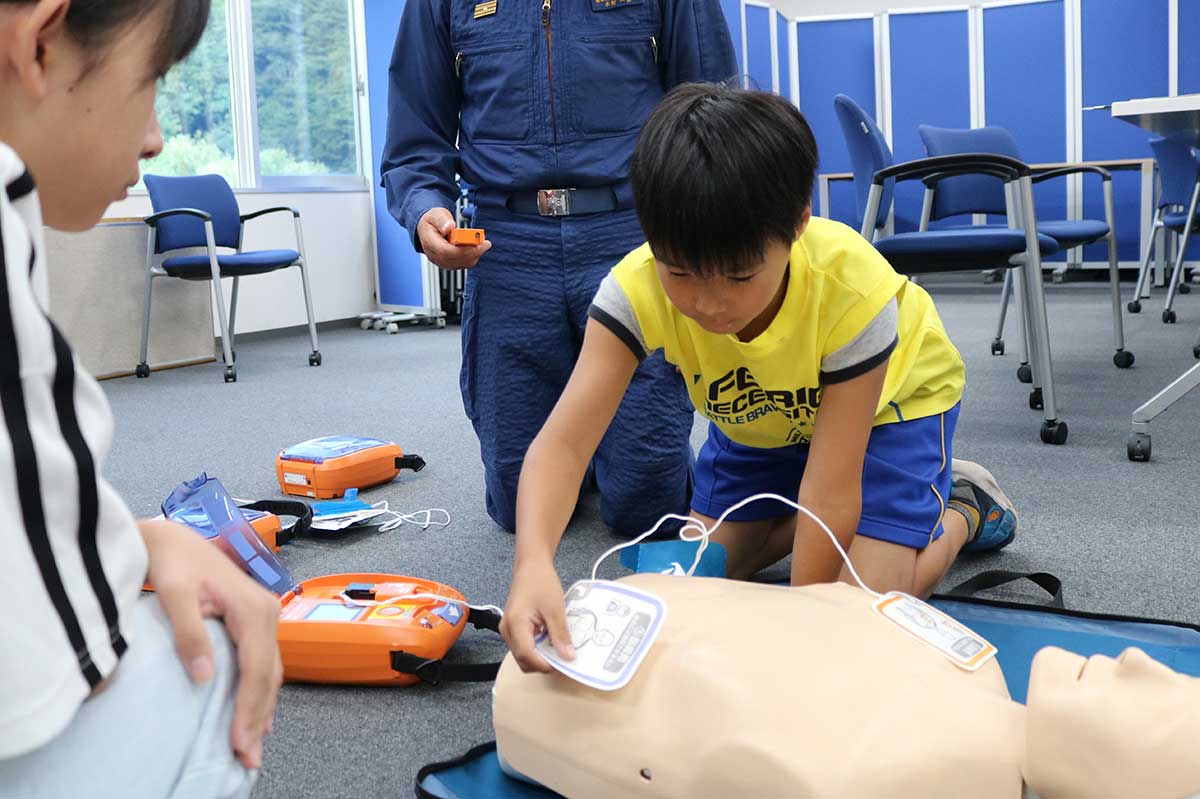 AEDの音声ガイドに従って電極パッドを人形の胸に貼り付ける