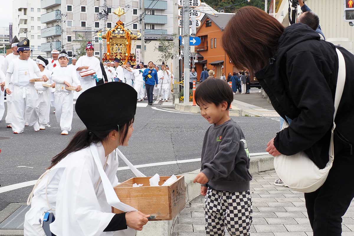 さい銭で気持ちのやりとりをする親子と行列参加者