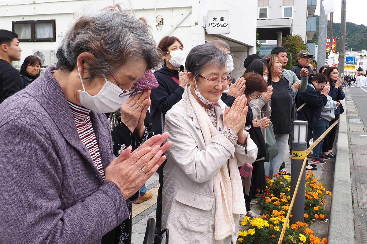 通りを練り歩く神輿に手を合わせる釜石市民ら