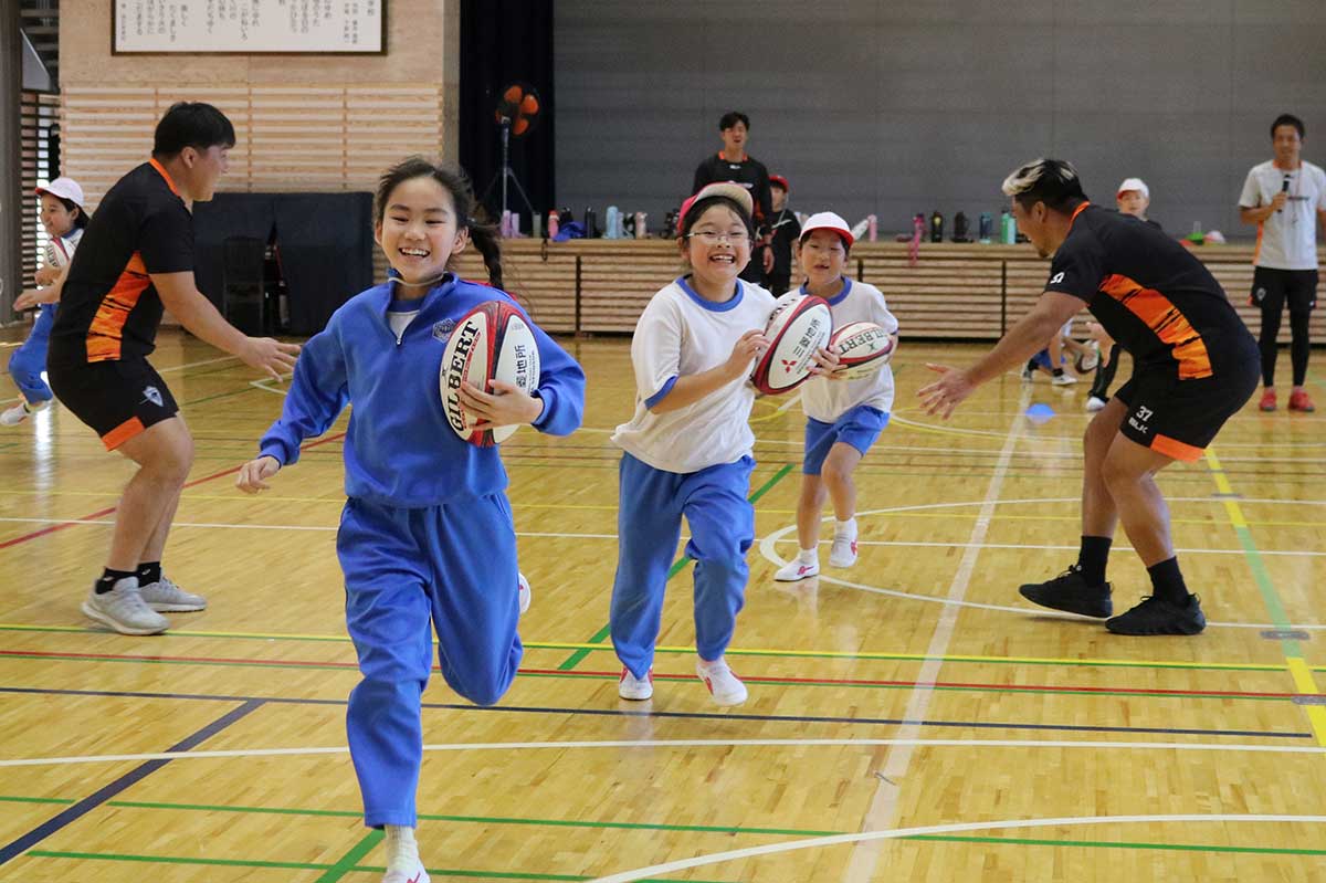 クボタスピアーズ船橋・東京ベイの選手らとラグビーで交流する鵜住居小児童=9月26日、同校体育館