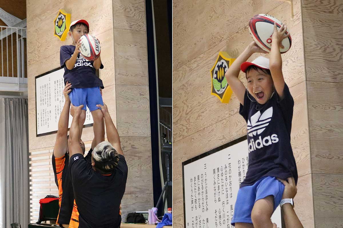 選手に体を持ち上げてもらい、ラインアウトを体験する児童