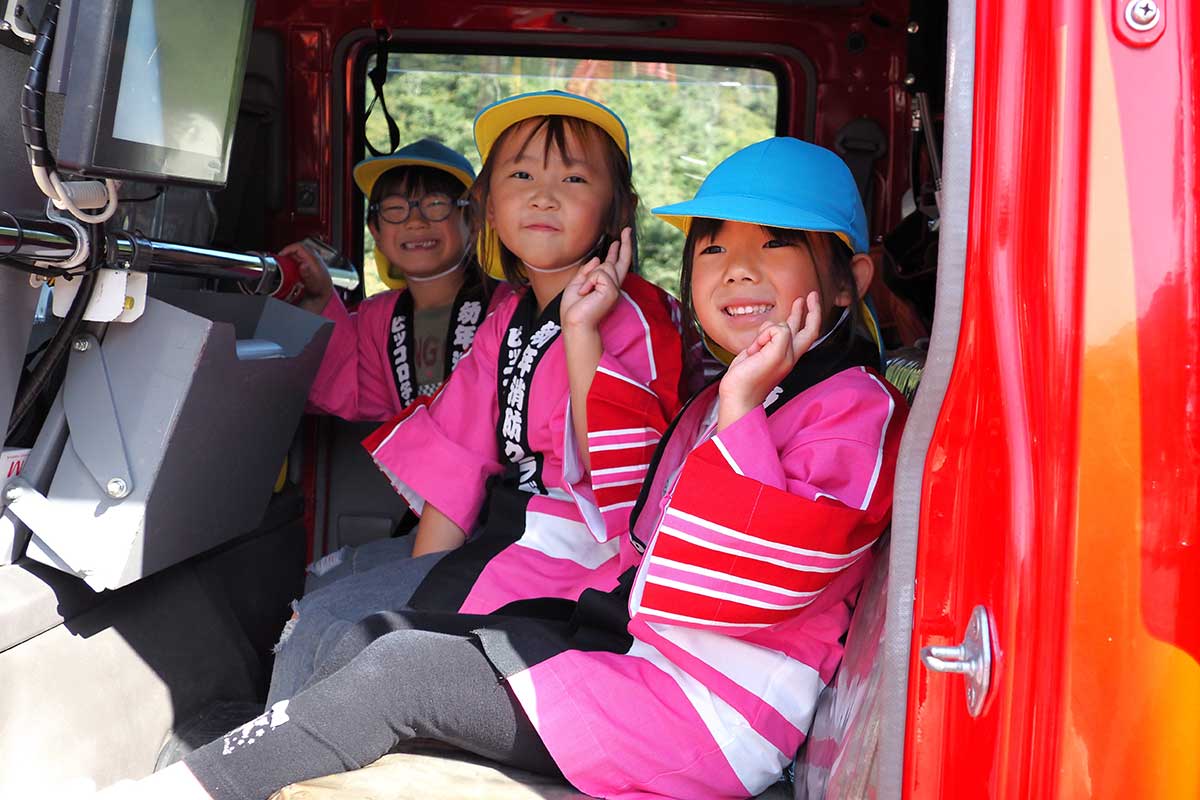 消防ポンプ車に乗って笑顔を見せる子どもたち