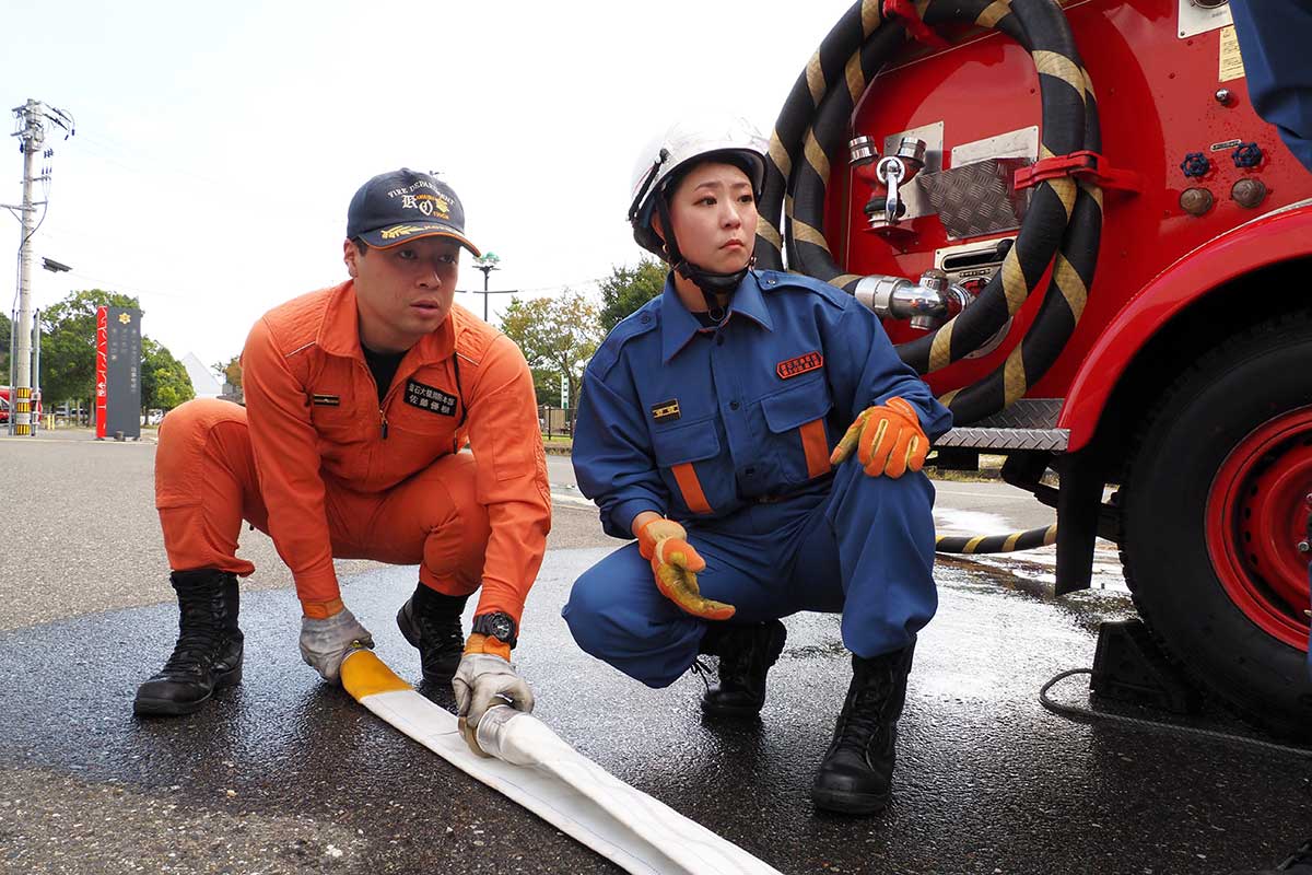 消防署員から教わりながら訓練に臨む小林真由美さん(右)