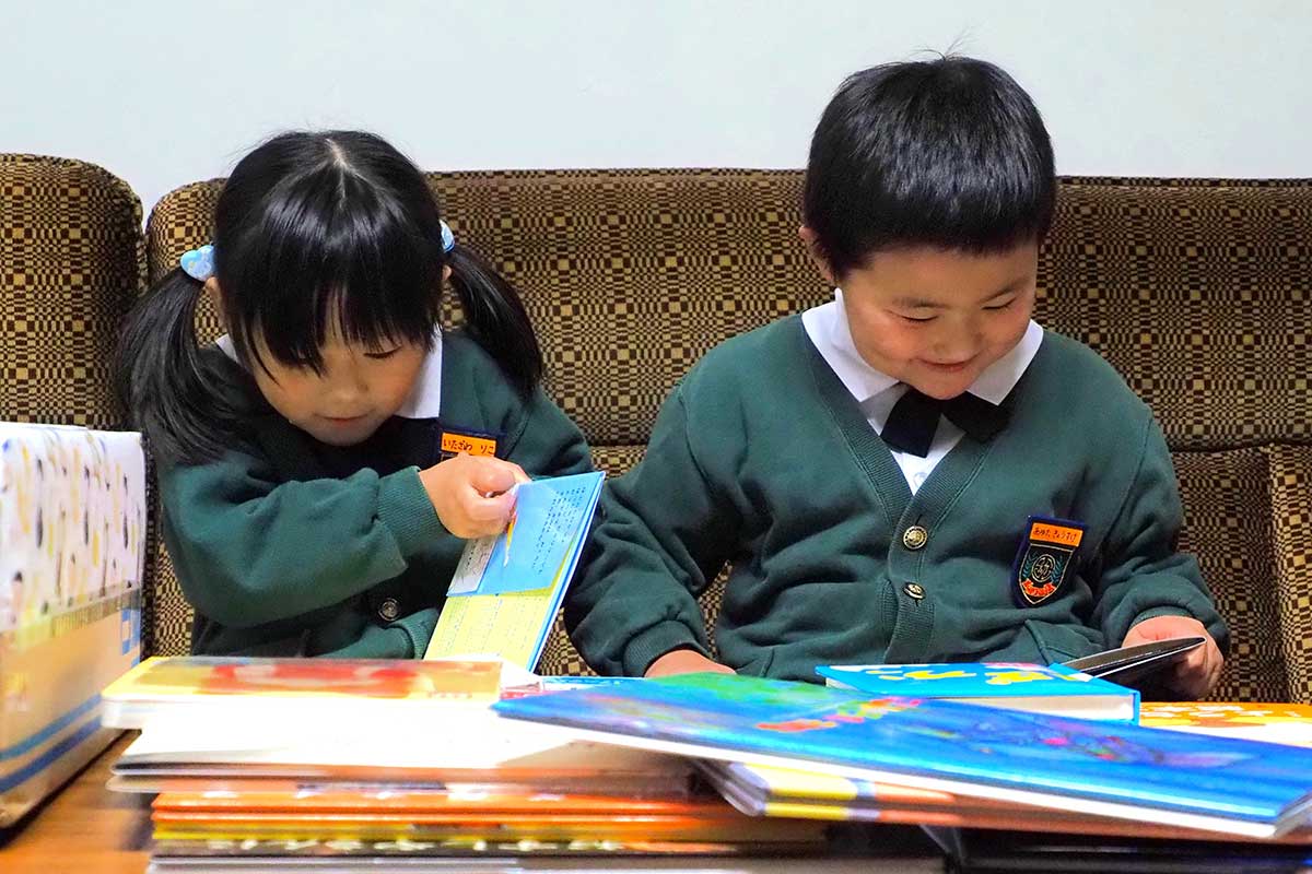 絵本のページをめくり笑顔になる甲東こども園の園児