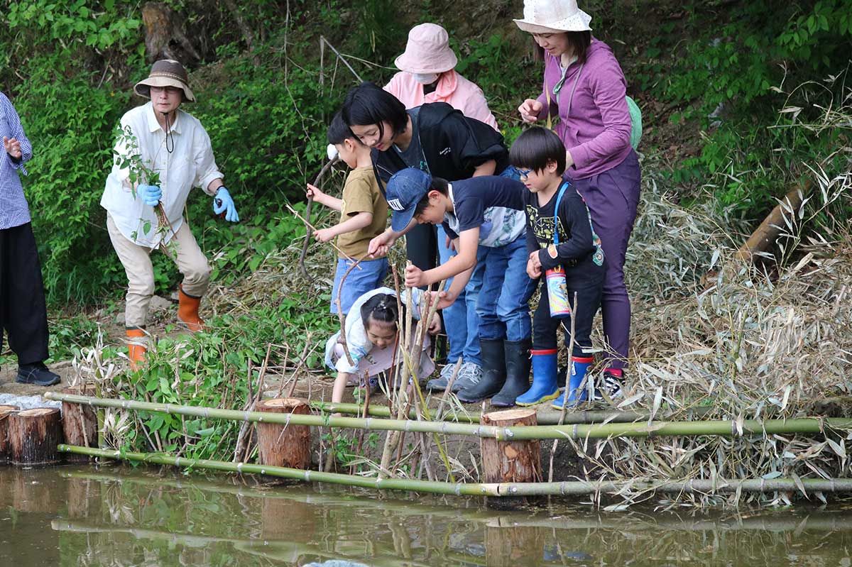ビオトープ完成後のお披露目イベントでは、参加者が池のほとりに生き物のすみかを作った＝2024年5月