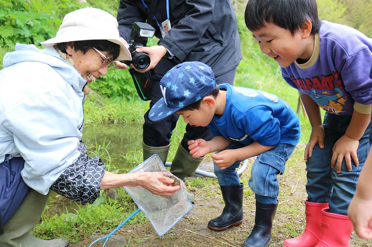 加藤代表（左）からトウホクサンショウウオの卵を見せてもらう子ども
