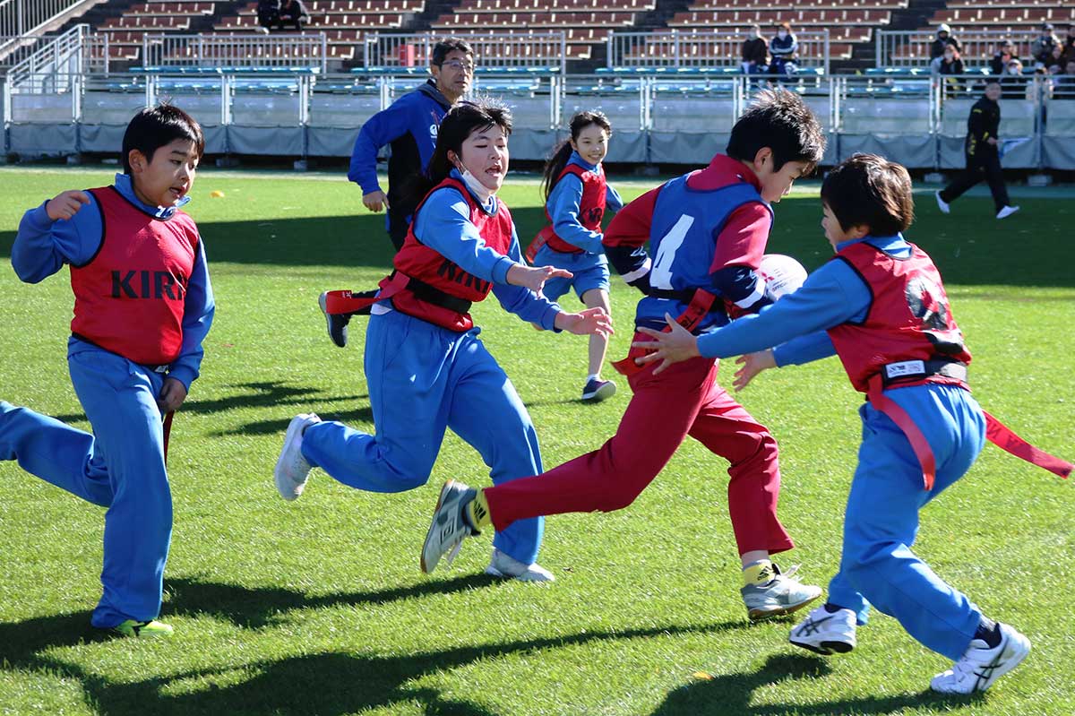 釜小タグラグビー戦隊クックルンAの攻撃を止めようとタグに手を伸ばす鵜住居ゴリラーズ（予選Bブロック）
