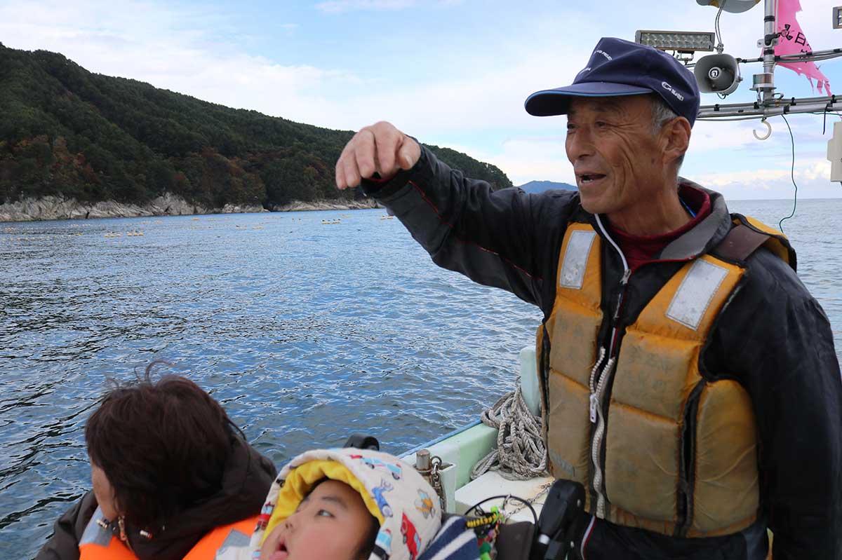 湾内の定置網漁について教える柏﨑之彦さん(右)