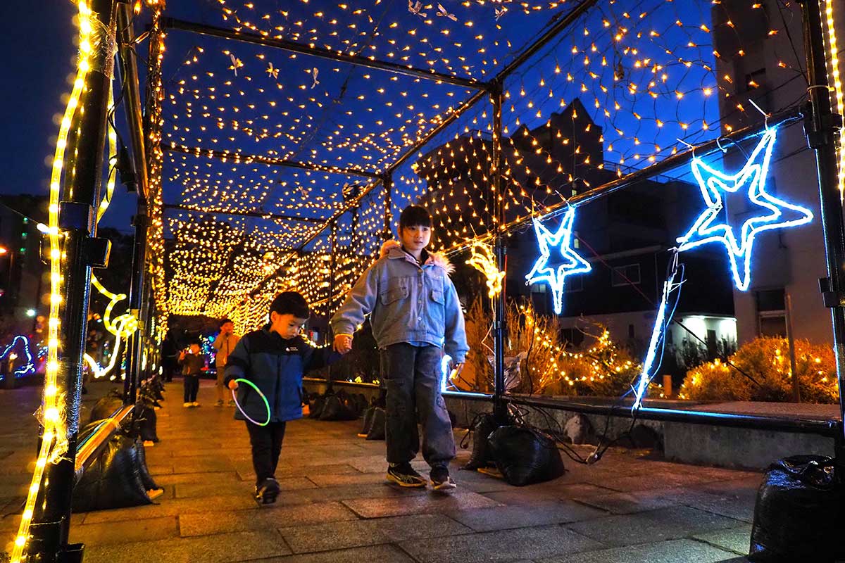星形のオブジェがきらめく光のトンネルを進む子どもたち