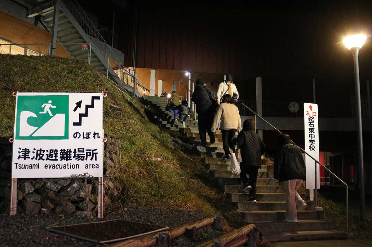津波警報発表で、避難所が開設されている鵜住居小・釜石東中体育館に急ぐ地元住民ら＝9日午前0時