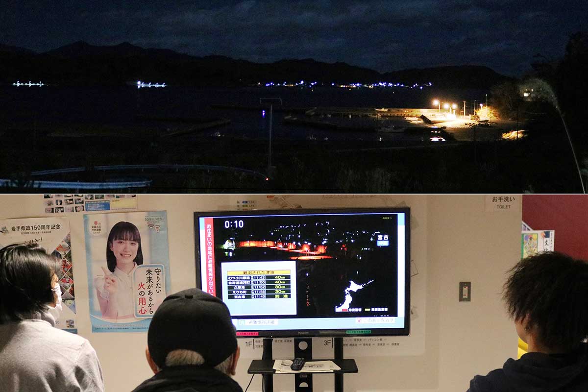 写真上：鵜住居町根浜の高台から見下ろす大槌湾＝9日未明。同下：避難所のテレビで情報収集する避難者ら（釜石東中校内）