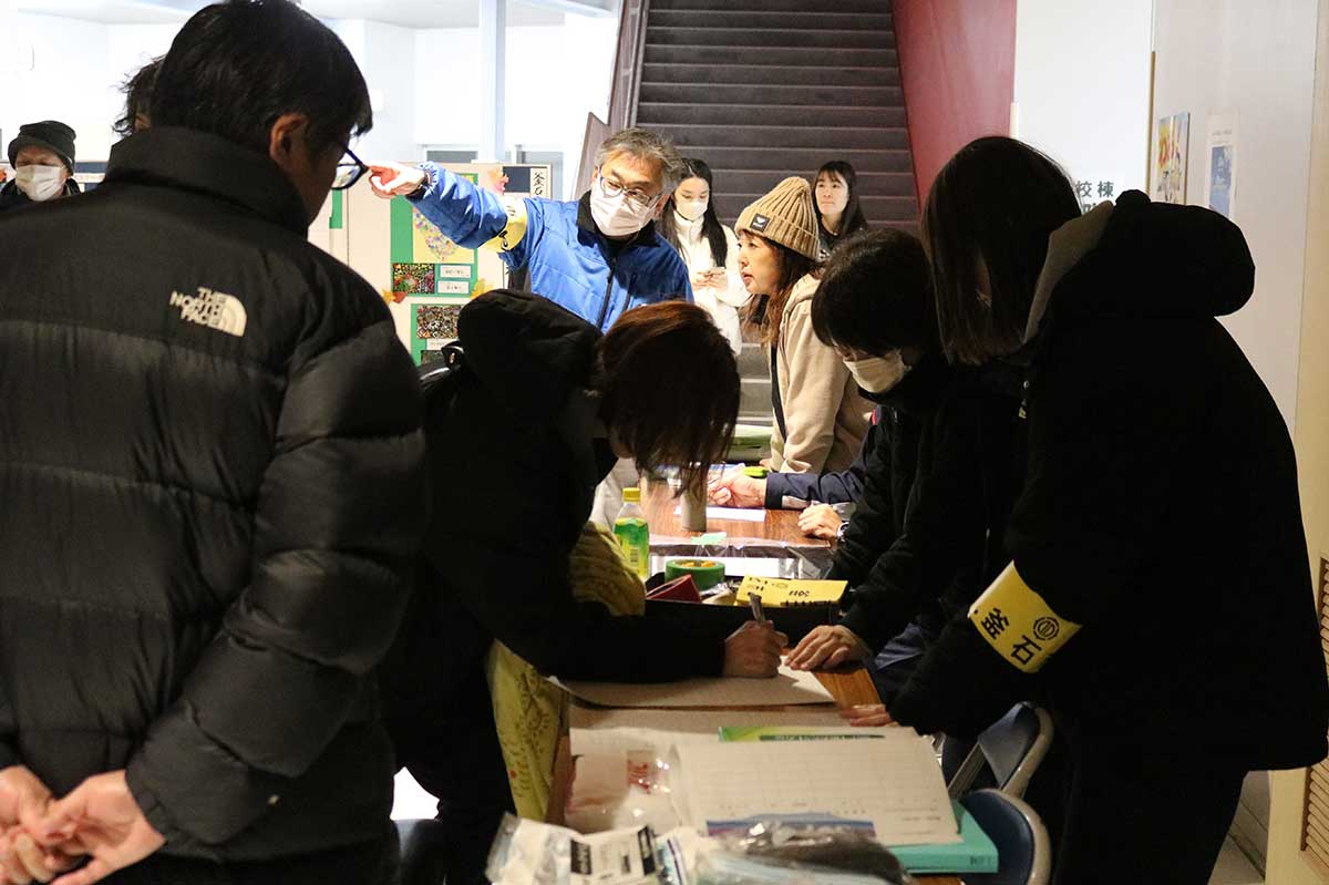 鵜小・東中体育館前の受付で氏名などを記入する避難者
