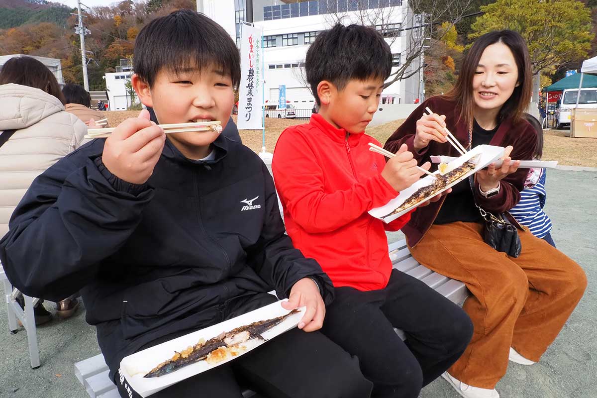 サンマを頬張る親子連れ「焼きたて、おいしい」