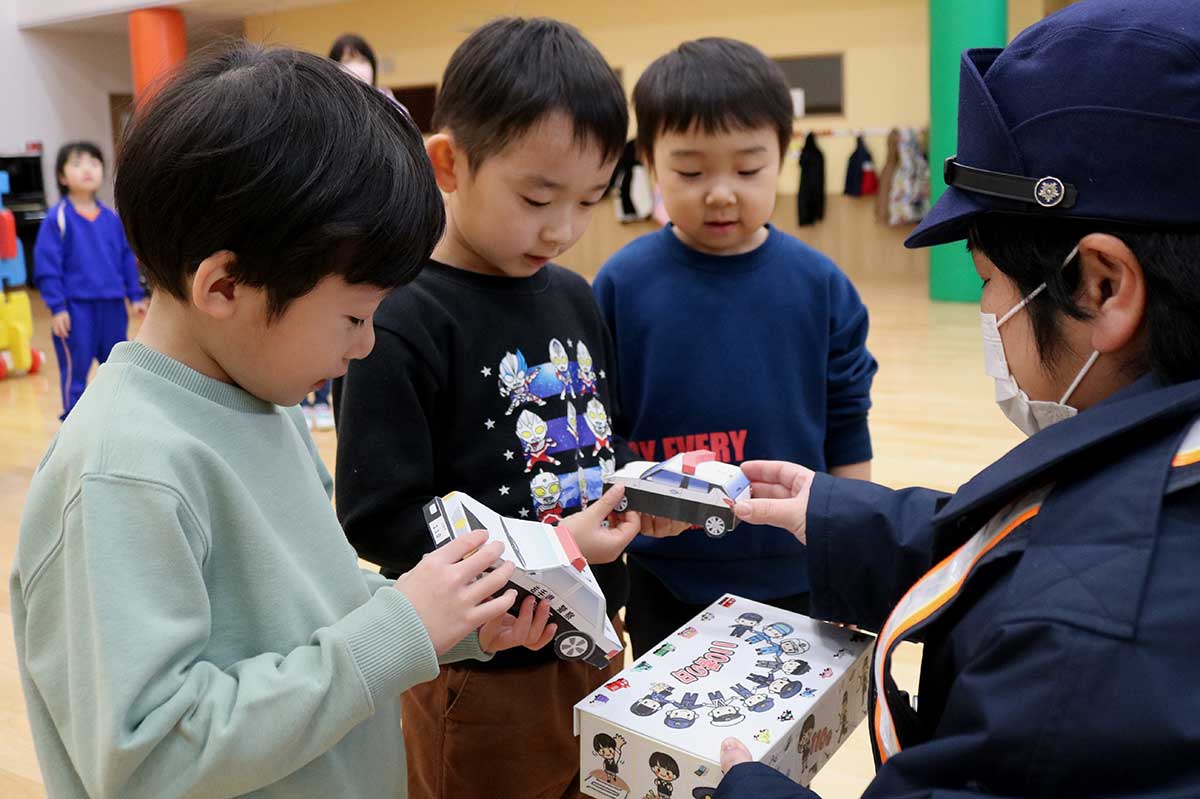 金野章子巡査部長（右）からクラフト作品を受け取る上中島こども園の園児ら＝9日