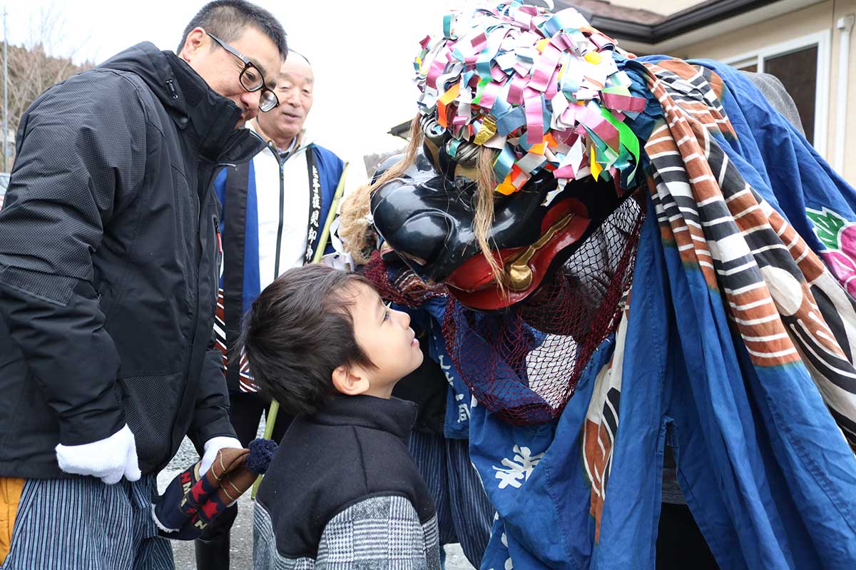 獅子頭に頭をかんでもらう子ども。邪気を吸い取ってくれるとされる