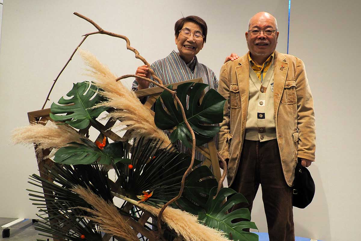 優しく支える夫の民男さんと寄り添い笑顔の村上さん