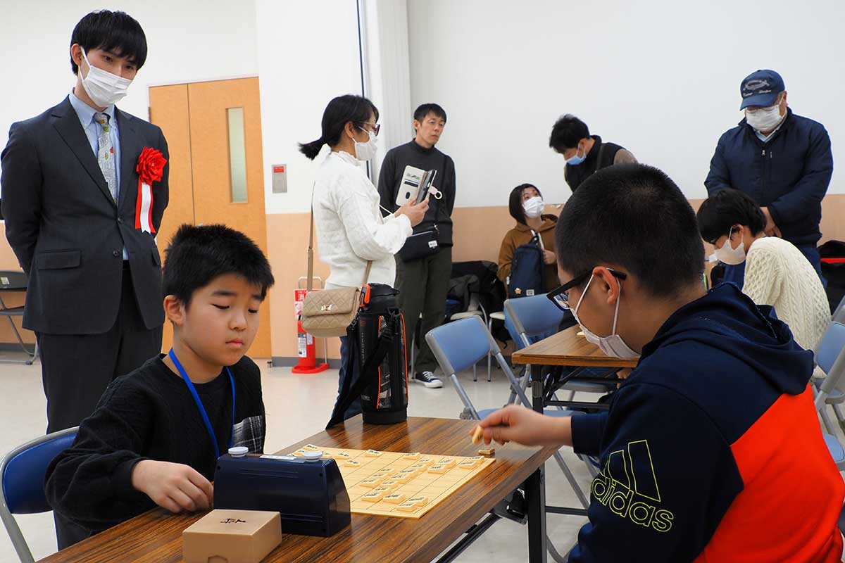 マスト子供将棋大会で熱戦の様子を見つめる小山四段