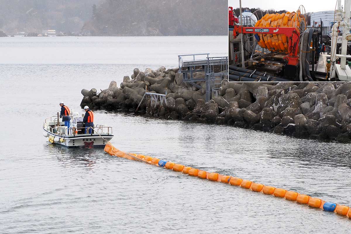油の広がりを抑えるためオイルフェンスを張る作業船