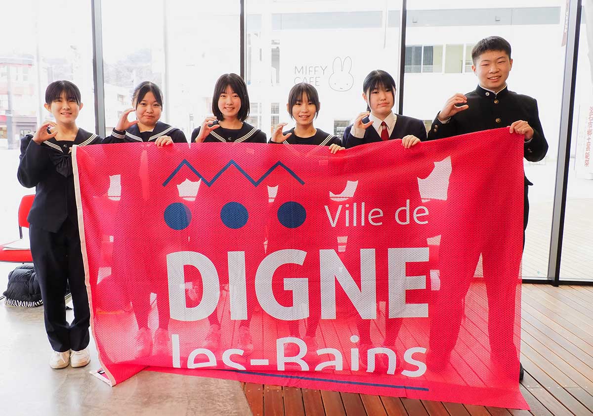 「メルC」と手でサインを示し笑顔を見せる生徒たち