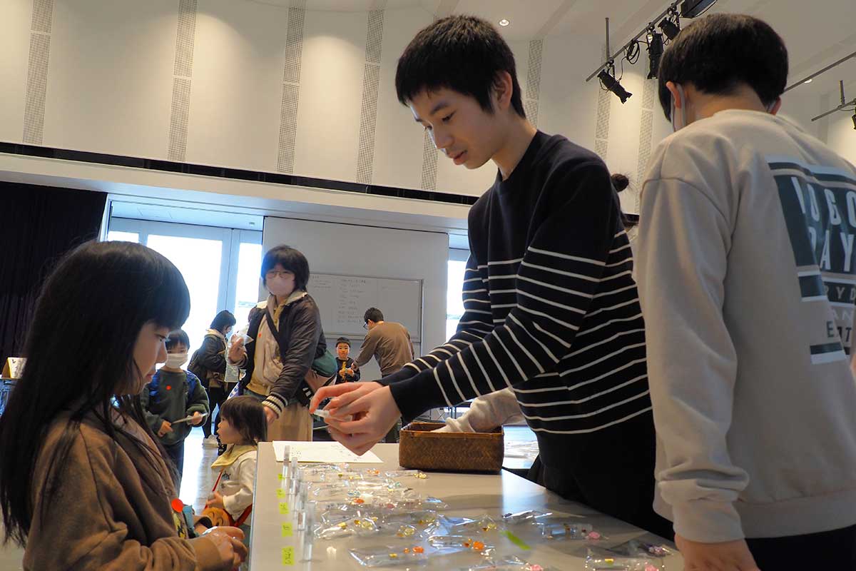 「これはどう？」と小さなお客様に商品をPRする中学生