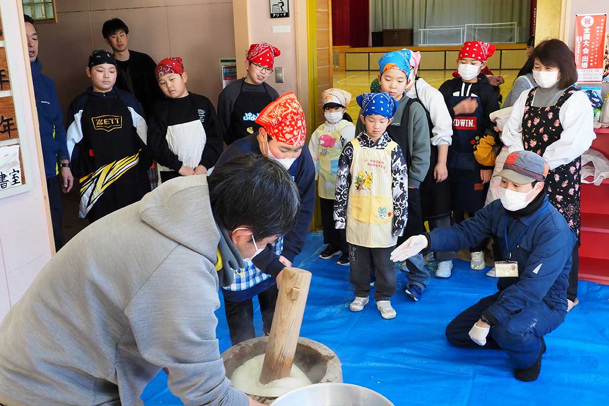 大人からアドバイスを受けながら餅つきに挑む子どもたち