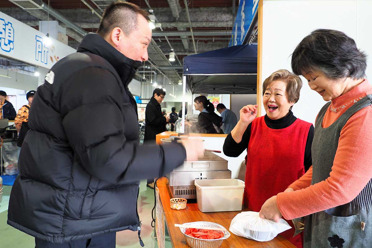 買い物客と笑顔を交換する「とんぼ」店主の高橋津江子さん(中)