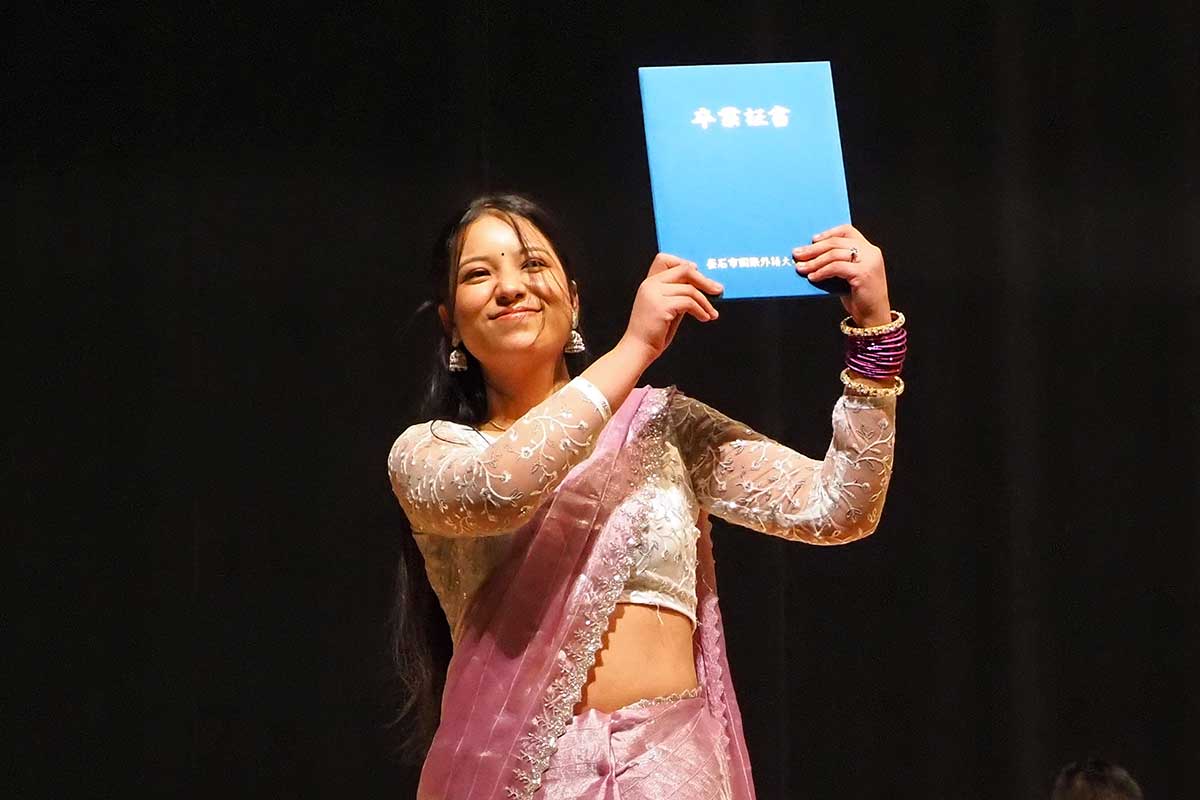 卒業証書を掲げて笑顔を見せる1期生