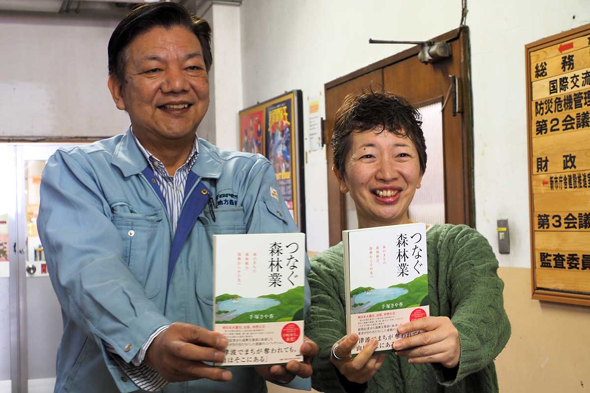 本を手にする著者の手塚さや香さん（右）と釜石地方森林組合の高橋幸男参事