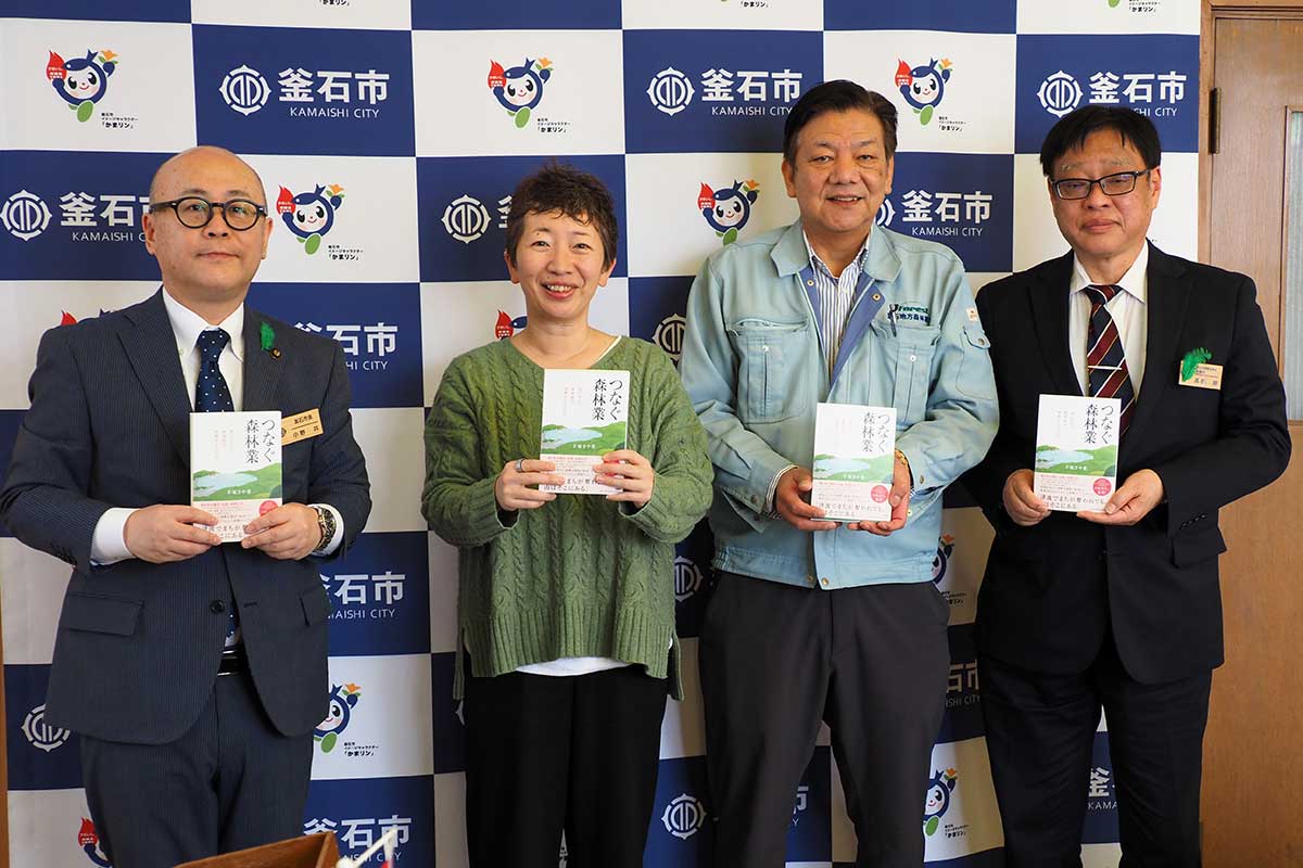 「子どもたちに林業の仕事を伝えてほしい」と小野共市長（左）に本を託した