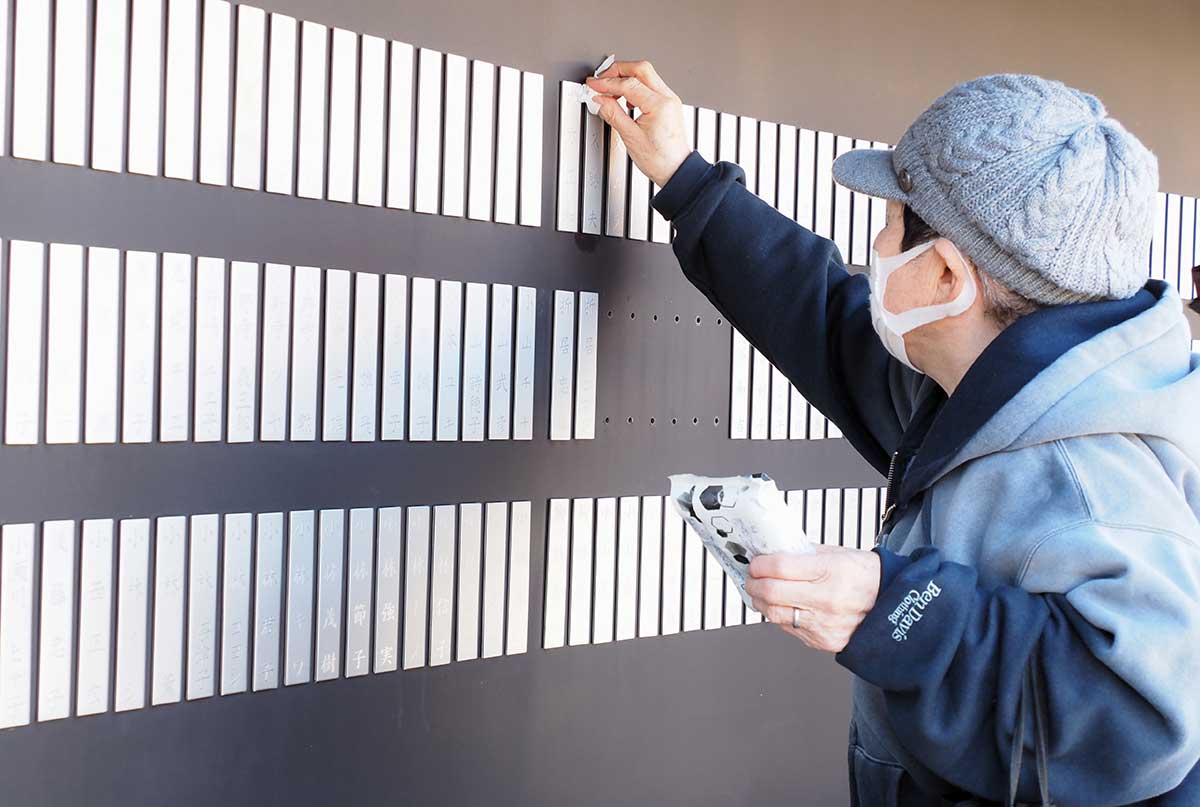 祈りのパークで亡き人を思い名前に手を伸ばす女性