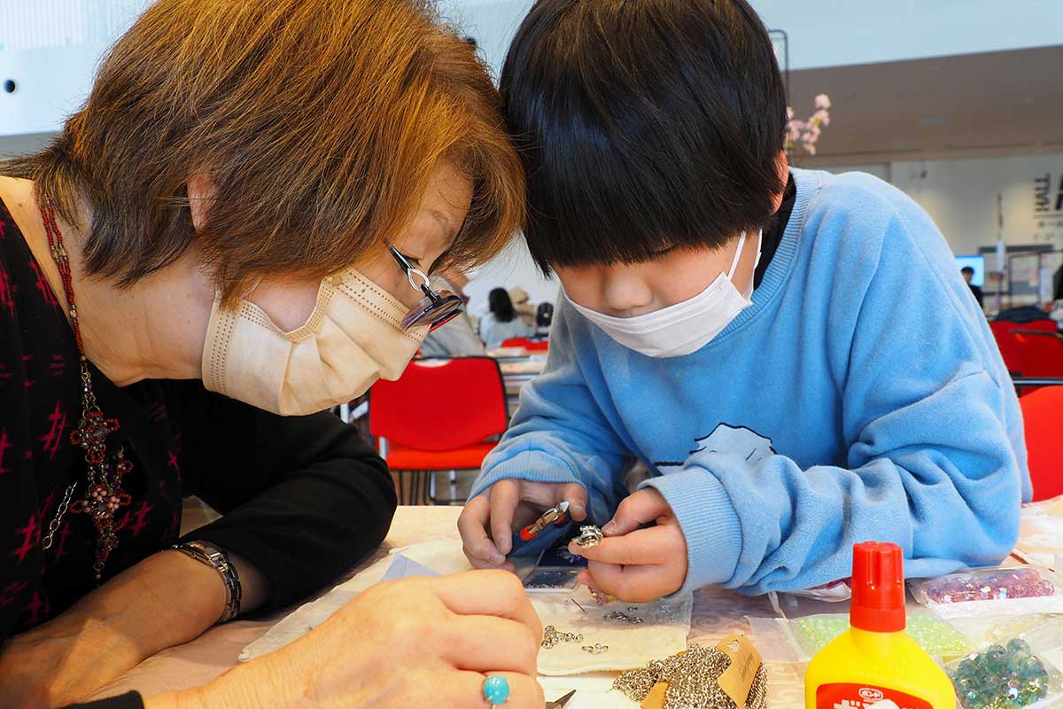 作業を見守りながら参加者との触れ合いを楽しむ講師（左）