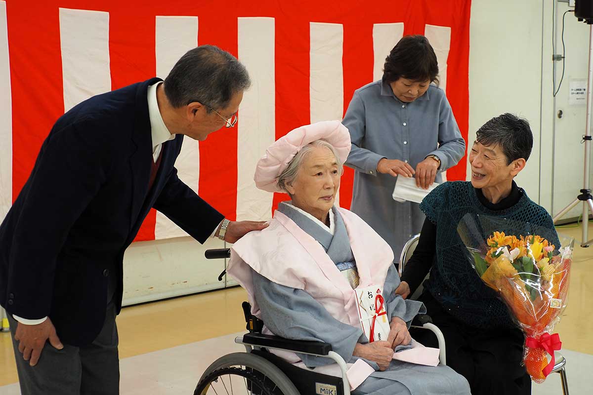 桃色のちゃんちゃんこ姿の板澤さんを家族が囲む