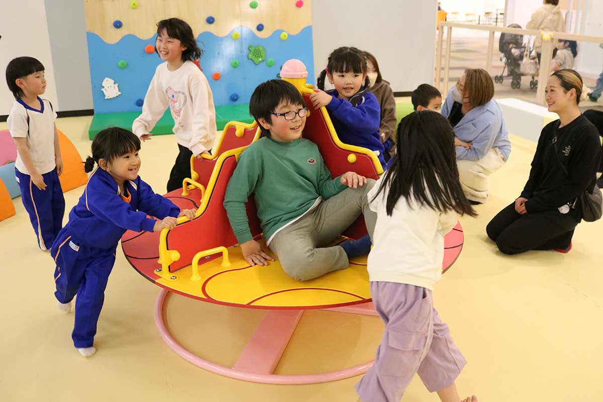 イソギンチャクをモチーフにした回転遊具に笑顔を広げる子どもたち