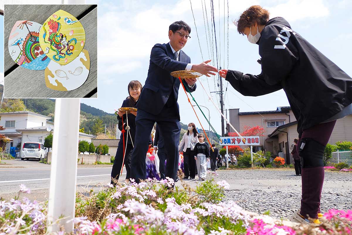 稚児行列を見にきた人に縁起物の「散華（さんげ）を手渡す